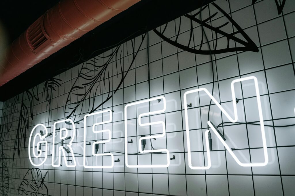 A neon sign spelling 'GREEN' on a tiled wall with a decorative design.