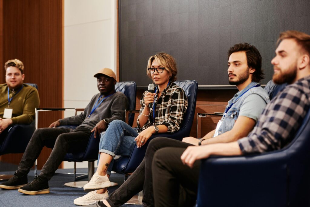 A diverse group of individuals engaged in an informative panel discussion at an indoor event.